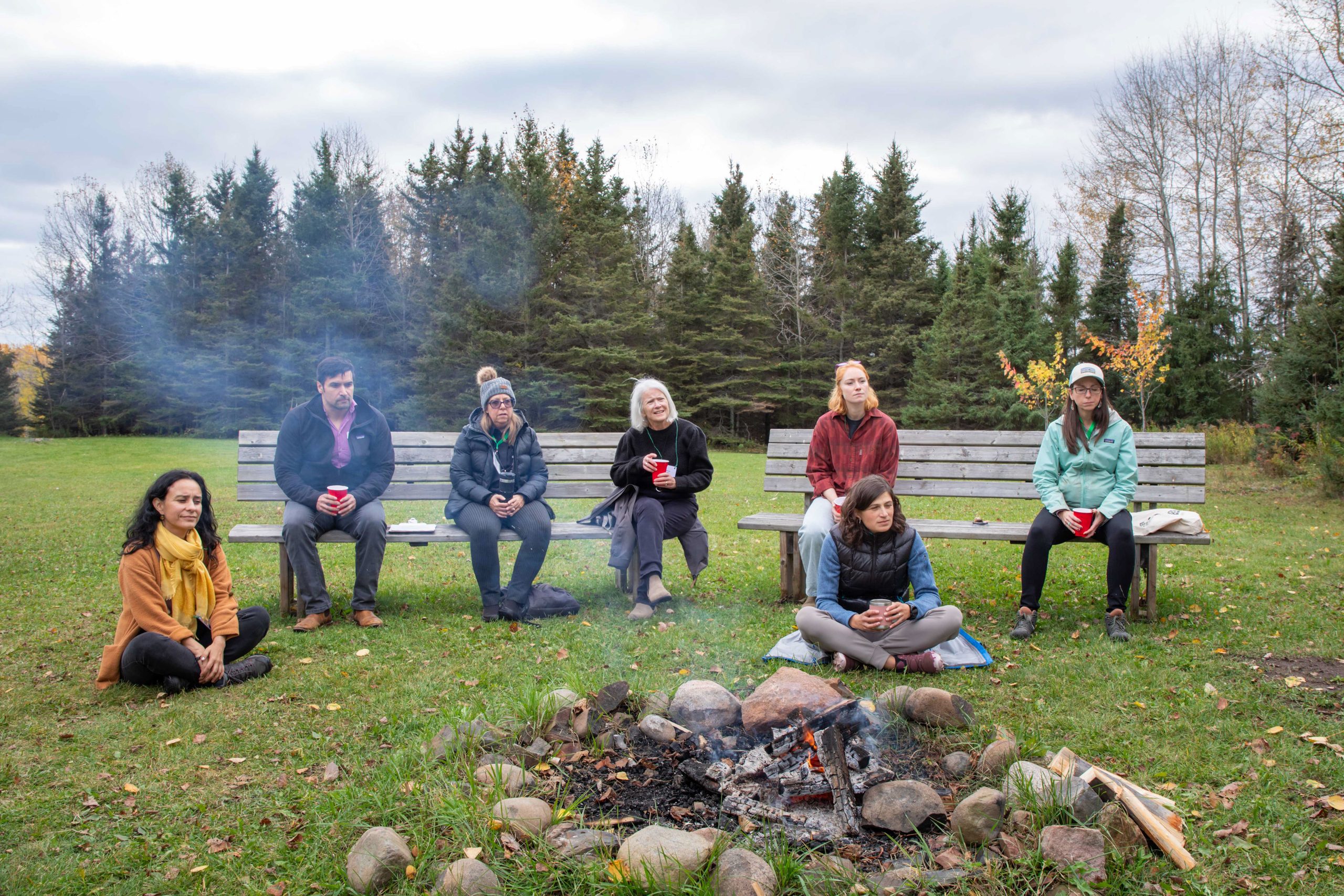 Six attendees at the Northwest Climate Gathering sitting in front of a fire, October 18, 2025, Lakehead University, Thunder Bay.